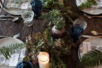 a greenery table runner with various types of it, succulents and air plants plus candles brings a touch of wild nature