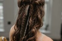 a half updo with a twisted halo and curls down spruced up with feathers for a boho feel