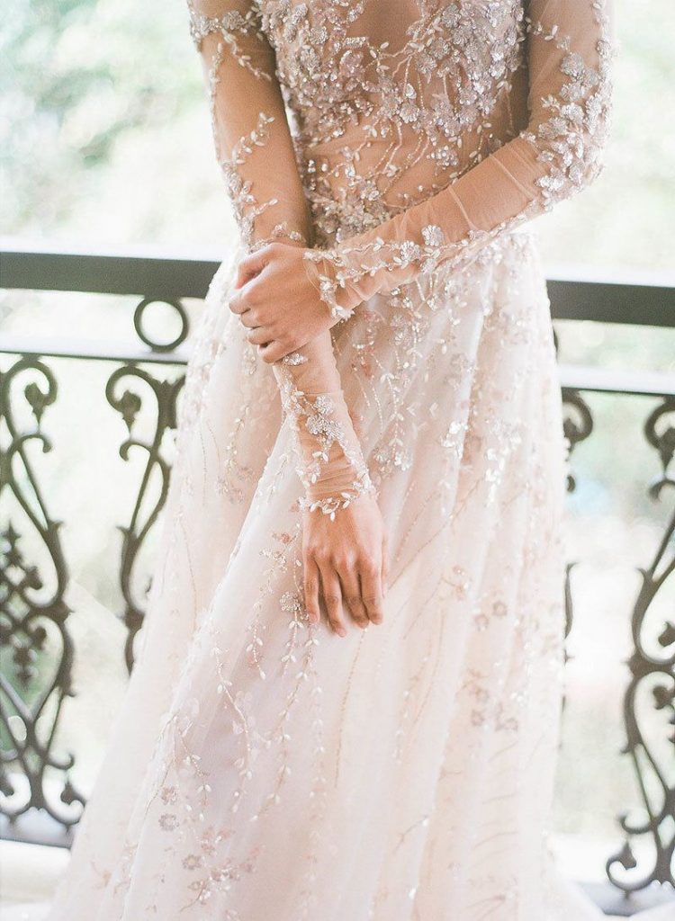 a jaw-dropping wedding dress with floral appliques and shiny embroidery, with intricate embellishments and long sleeves