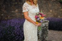 a lace applique mermaid wedding dress with short sleeves, a high neckline and a long train