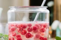 a large jar with lemonade with raspberries is a cool idea for a spring shower drink