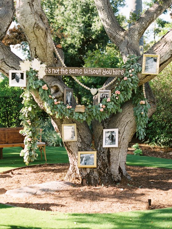 a living tree with wooden bead decor, greenery and blooms and black and white photos as a memorial at a wedding
