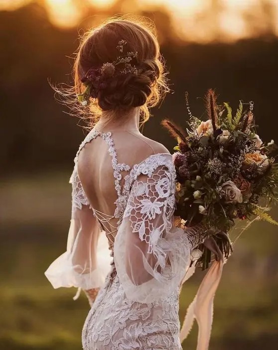 a low braided and twisted updo with herbs and blooms is a great idea for a boho bride