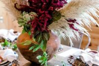 a lush boho wedding centerpiece with purple blooms, greenery and pampas grass for a bright touch