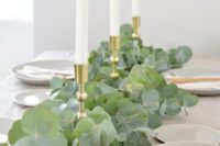 a lush eucalyptus table runner combined with gold candle holders and tall candles is timeless classics