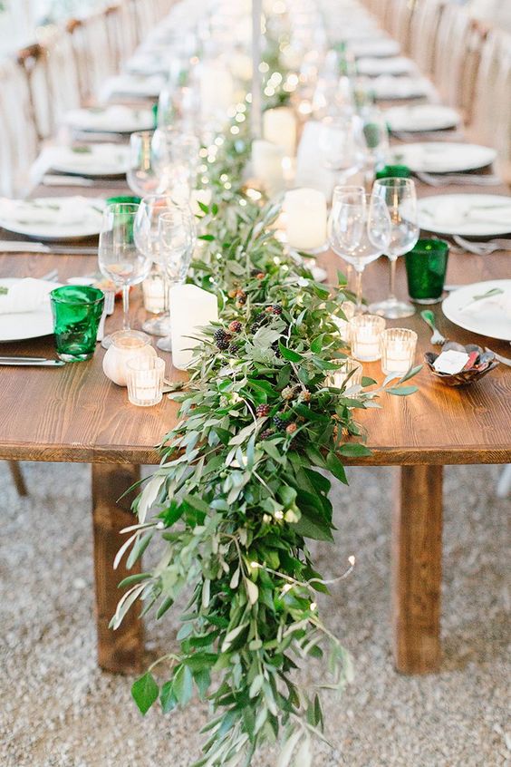 a lush greenery table runner with some berries is ideal for a summer woodland wedding