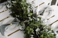a lush greenery table runner with various kinds of eucalyptus, moss and ferns is very wild-like