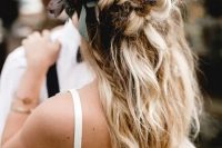 a messy textural half updo with twists and braids and greenery and feathers
