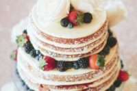 a mouth-watering naked wedding cake with white blooms and fresh berries is a lovely dessert for a rustic wedding