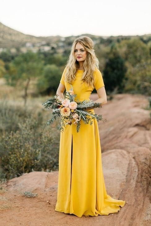 a mustard weddin dress with a high neckline, short sleeves, a front slit and a short train
