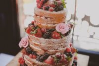 a naked wedding cake with fresh berries and pink sugar blooms is a delicious dessert for a summer rustic wedding