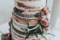 a naked wedding cake with sugared berries and greenery for a summer rustic wedding
