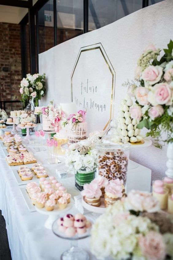 a pink sweets bar with various kinds of pink and blush sweets, cakes with pink blooms and greenery