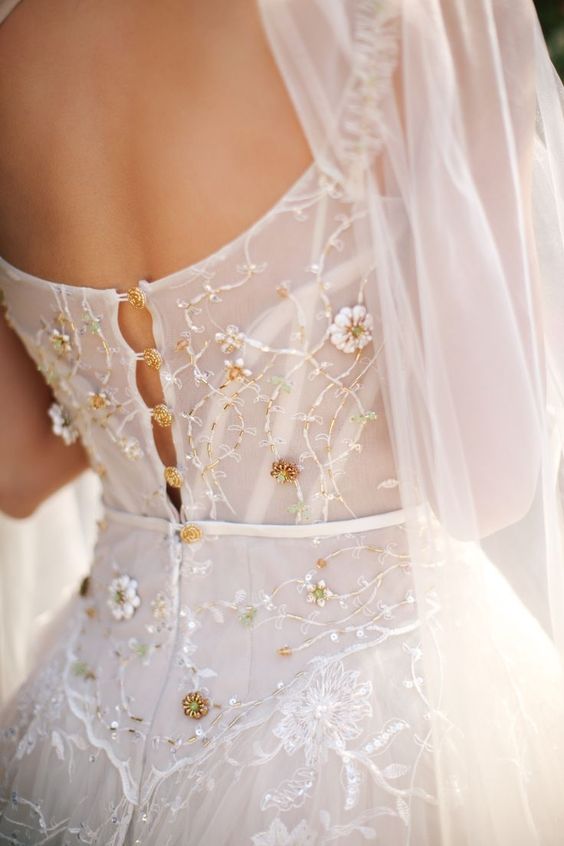 a refined fitting wedding dress with floral appliques and embellishments, with gold buttons to match the embellishments