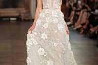 a romantic A-line neutral wedding dress embellished with shimmering beadwork and 3D floral appliques, spaghetti straps, a deep plunging neckline