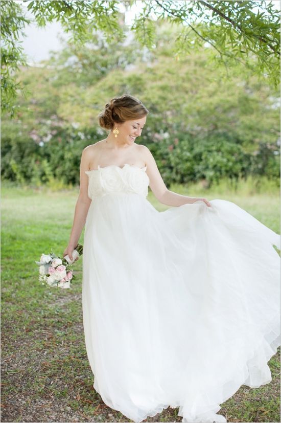 a romantic empire waist wedding ballgown with a floral applique bodice and a layered skirt, statement earrings