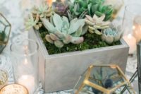 a simple boho wedding centerpiece with succulents planted in a box, candles and terrariums with succulents