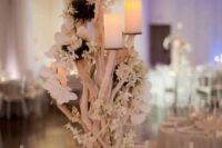 a spectacular beach wedding centerpiece with white blooms and candles on stands is a refined idea