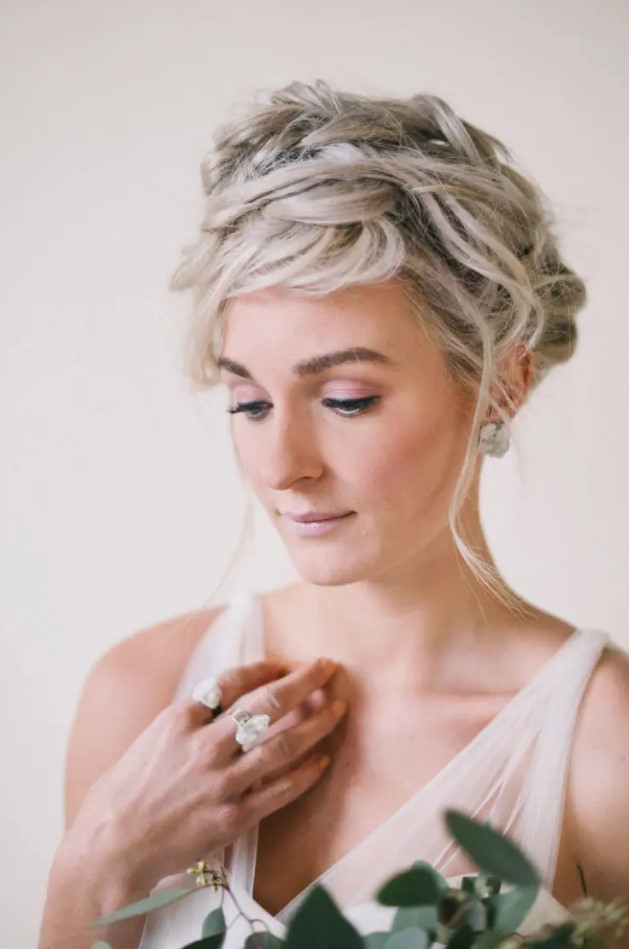 a super messy braided wedding updo with some locks down is a fit for both a minimalist or boho bride