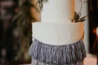a textural white wedding cake with ombre macrame and some greenery for a spring boho wedding