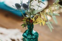 a turquoise bottle with eucalyptus, thistles and blooms is a great boho wedding centerpiece