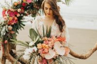 a unique wedding arch of driftwood, tropical leaves and bright tropical blooms is a fantastic idea