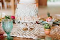 a white gradient wedding cake in white, mint, copper, peachy, with bright blooms and cacti on top and macrame detailing