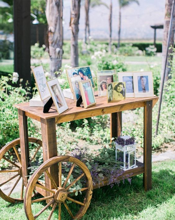 a wooden cart with photos, blooms and a candle lantern is a memorial at a wedding to commemorate all the people who are gone