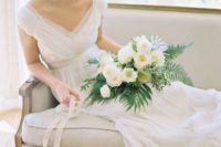 an airy and romantic wedding dress with a deep V-neckline, cap sleeves, a draped bodice, an empire waist and a pleated skirt