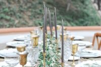 an elegant al fresco tablescape with an olive branch table runner and gold candle holders and grey candles