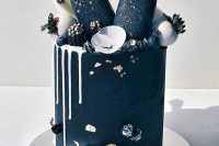 an exquisite black groom’s cake with white drip, black and gold popsicles, white chocolate shards, chocolate berries and gold leaf