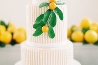 a beautiful striped wedding cake with tan and white stripes and ribbons, with kumquats and leaves for a modern wedding