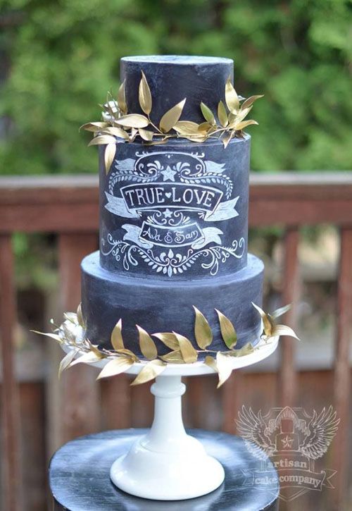 a black chalkboard wedding cake with chalking and gold leaf wreaths is a lovely solution for a modern wedding, a fall one
