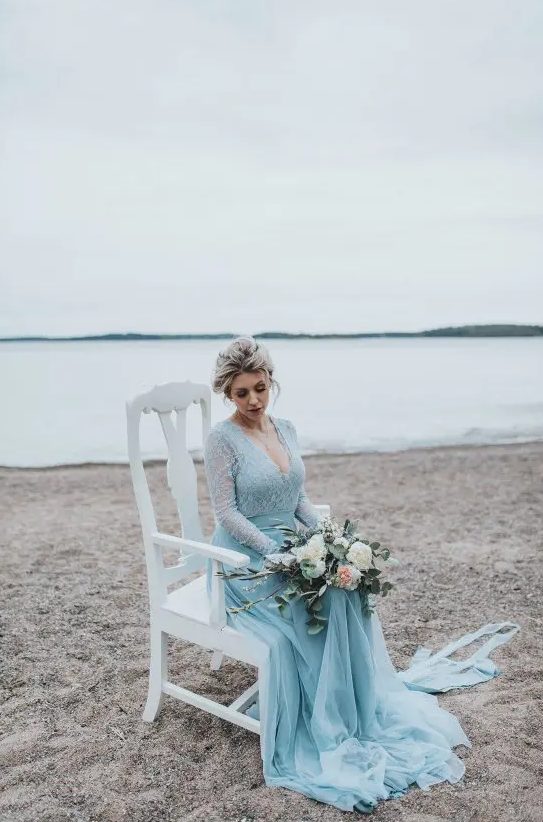 a blue wedding dress with a lace bodice, long sleeves, a layered skirt with a train and a deep V-neckline