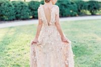 a blush A-line wedding dress with a low bakc and a train, with floral appliques is very refined