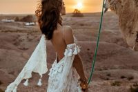 a boho A-line wedding dress in white, with gold lace detailing, tassels, a low back and a cold shoulder is very refined and chic