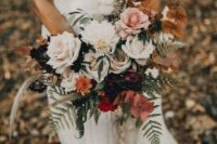 a boho fall wedding bouquet of white, pink and red blooms, deep purple ones, dried leaves and green ones