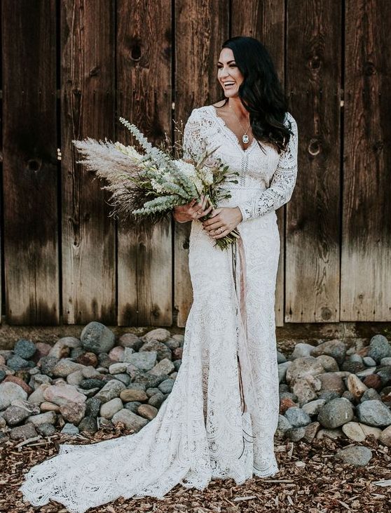a boho lace mermaid wedding dress with long sleeves and a train plus a V-neckline for a boho barn bride