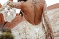 a boho mermaid wedding dress in white with gold lace detailing, a low back, bell sleeves and a train is chic