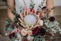 a boho summer wedding bouquet of greenery, blush and purple blooms, a giant king protea and eucalyptus