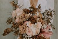 a boho wedding bouquet of blush and coffee colored blooms, dried leaves and grasses for a fall bride