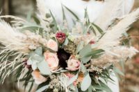 a boho wedding bouquet of blush and deep purple blooms, greenery and pampas grass is awesome