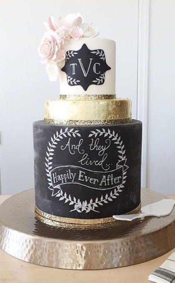 a bold and chic wedding cake with a chalkboard, gold and white tier, with a chalkboard mark, pink blooms and gold glitter is amazing