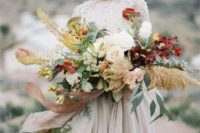 a bold fall wedding bouquet with burgundy and white blooms, greenery and pampas grass plus long ribbons