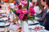 a bold tropical wedding table with woven chargers, bright blooms and greenery and fruits is bright classics