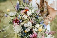 a bright boho summer wedding bouquet of white, pink, yellow, orange blooms, greenery and textural touches