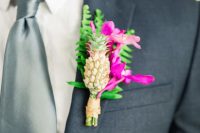 a bright tropical wedding boutonniere with hot pink blooms, greenery and a mini pineapple is a lovely idea