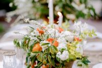 a bright wedding tablescape with greenery, white and orange blooms, kumquats, thin candles is a lovely idea for spring or summer
