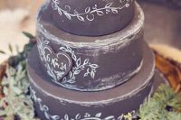 a chalkboard wedding cake with chalking, with a chalkboard heart and some textural greenery on and around the cake