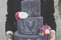 a chalkboard wedding cake with chalking, with neutral and bold blooms, with silhouette toppers is a gorgeous idea for a modern wedding